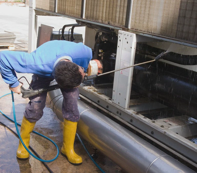 mężczyzna myjący maszynę wodą